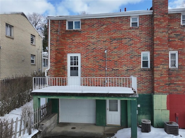 snow covered property with a garage, central AC, and a balcony