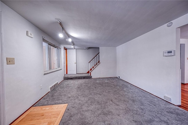 basement with track lighting and dark carpet