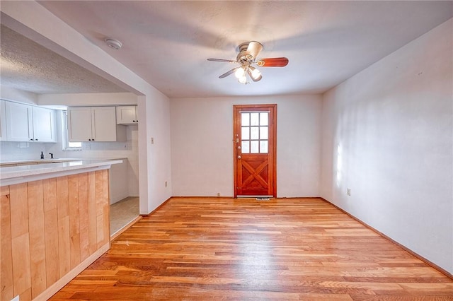 kitchen with white cabinetry, plenty of natural light, ceiling fan, and light wood-type flooring