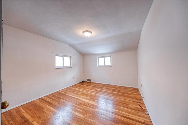 additional living space with vaulted ceiling and light hardwood / wood-style floors