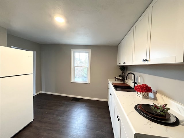 kitchen featuring white refrigerator, sink, dark hardwood / wood-style floors, light stone countertops, and white cabinetry