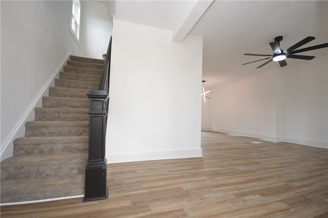 stairs featuring ceiling fan, hardwood / wood-style flooring, and beamed ceiling