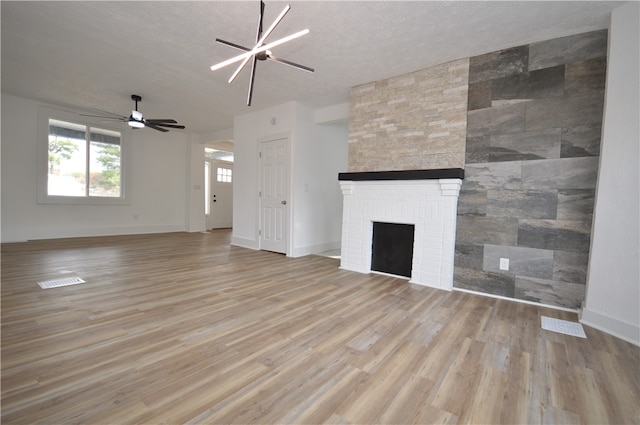 unfurnished living room with light hardwood / wood-style flooring, a textured ceiling, and a fireplace