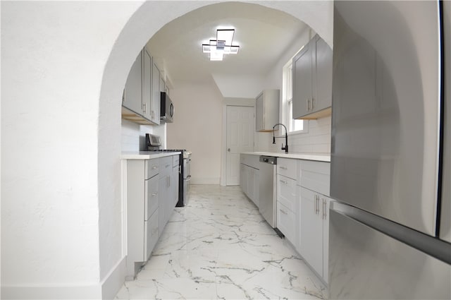 kitchen with appliances with stainless steel finishes, sink, and gray cabinetry