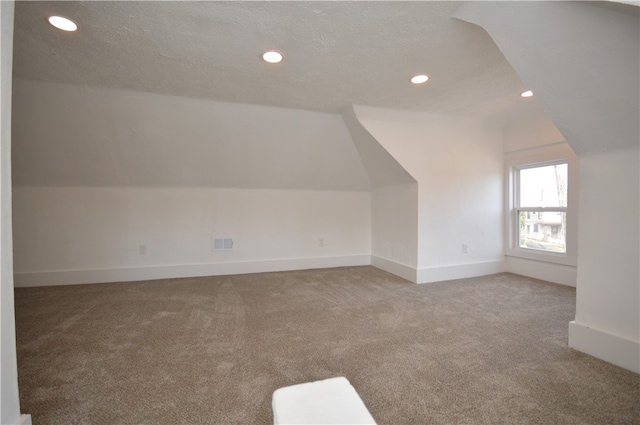 additional living space featuring a textured ceiling, vaulted ceiling, and carpet floors