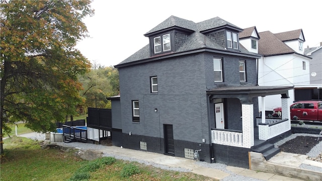 view of side of home featuring covered porch and a trampoline