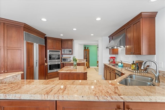 kitchen featuring extractor fan, built in appliances, kitchen peninsula, sink, and light stone countertops