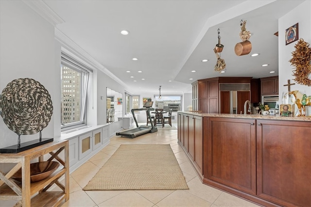 interior space with sink, crown molding, light tile patterned floors, and paneled fridge