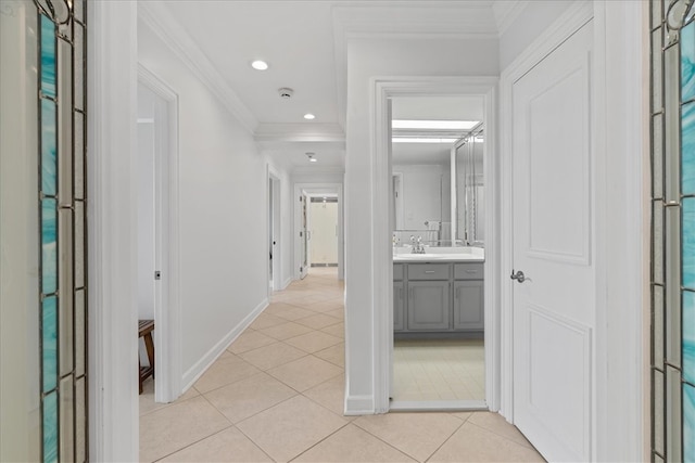 hallway with sink, crown molding, and light tile patterned floors