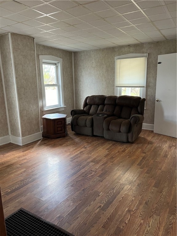 living room featuring dark wood-type flooring and a paneled ceiling