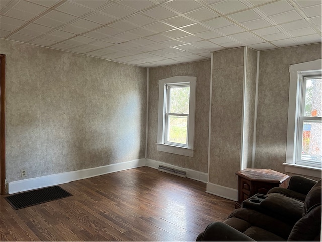 interior space featuring dark wood-type flooring, a paneled ceiling, and plenty of natural light