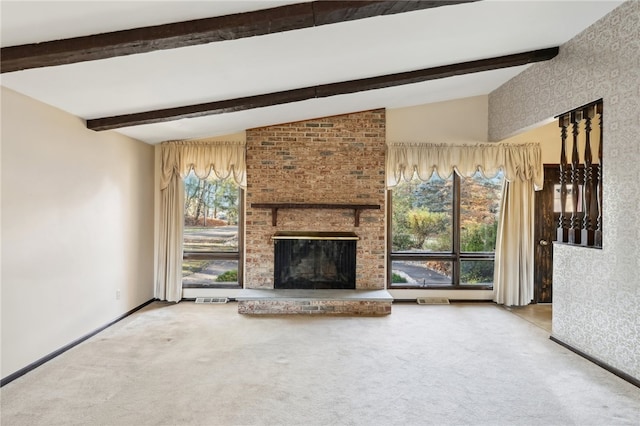 unfurnished living room with lofted ceiling with beams, carpet flooring, a wealth of natural light, and a brick fireplace