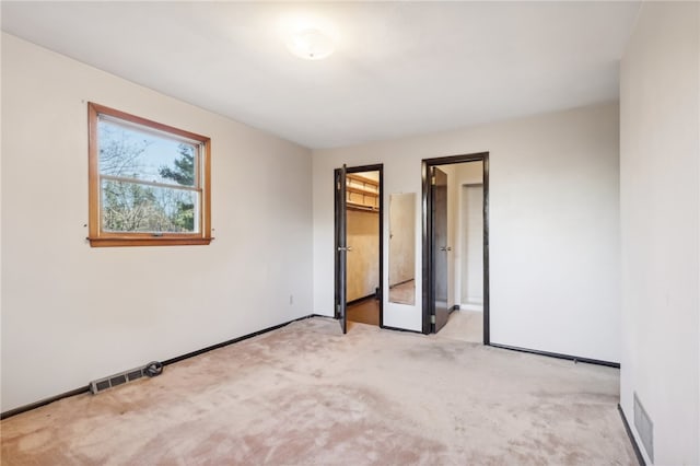 unfurnished bedroom featuring a closet, light carpet, and a spacious closet