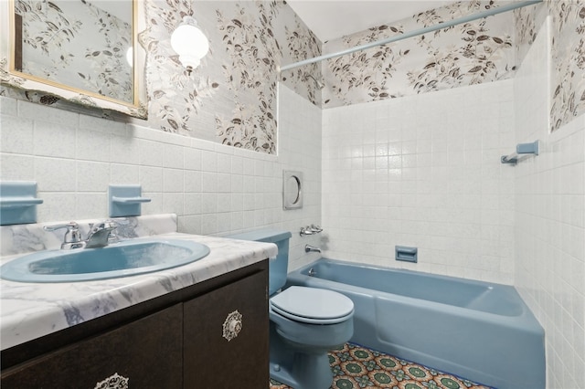 full bathroom with vanity, tiled shower / bath, toilet, and tile walls