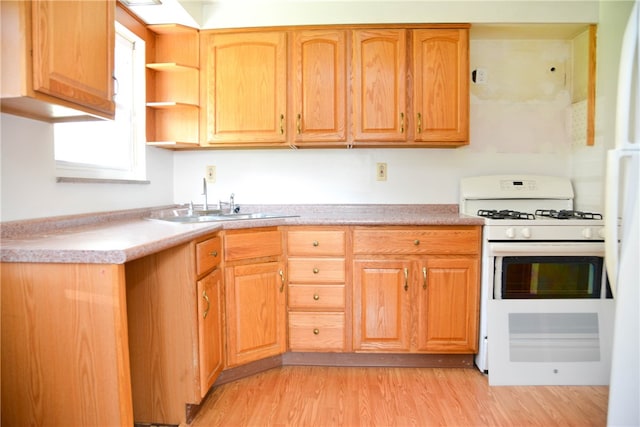 kitchen with gas range gas stove, sink, and light wood-type flooring