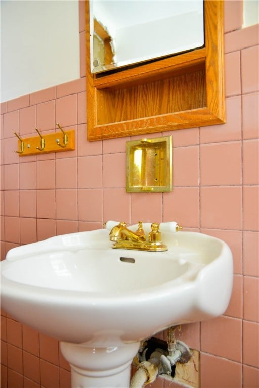 bathroom with backsplash, tile walls, and sink