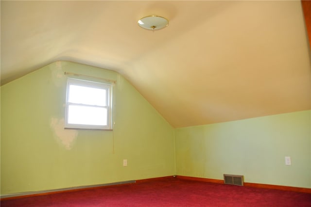 additional living space featuring vaulted ceiling and carpet floors