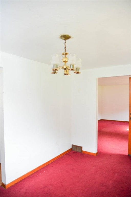 empty room with carpet floors and an inviting chandelier