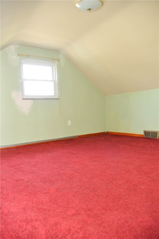 bonus room with carpet flooring and vaulted ceiling