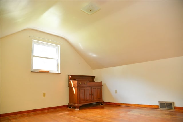 additional living space featuring lofted ceiling and light hardwood / wood-style flooring