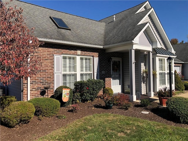 view of front of house featuring brick siding, a shingled roof, and a garage