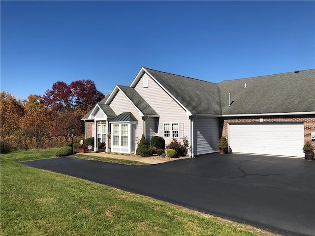 view of front facade with brick siding, a garage, aphalt driveway, and a front yard