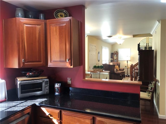 kitchen featuring a toaster, dark countertops, brown cabinets, and open floor plan