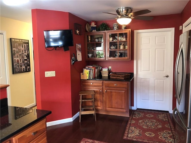 bar featuring freestanding refrigerator, ceiling fan, dark wood finished floors, and baseboards