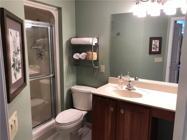 bathroom featuring toilet, a shower stall, and vanity