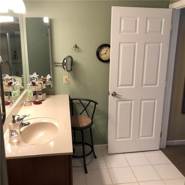 full bathroom with an enclosed shower, baseboards, vanity, and tile patterned floors