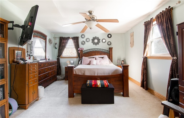 bedroom featuring multiple windows, light colored carpet, and ceiling fan