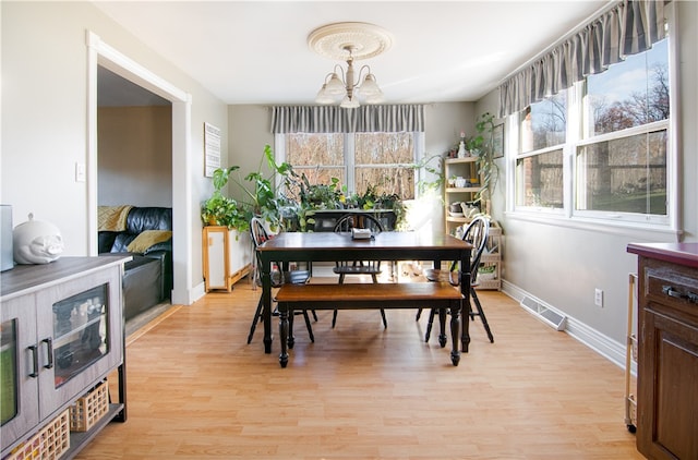 dining space featuring light hardwood / wood-style floors and a chandelier