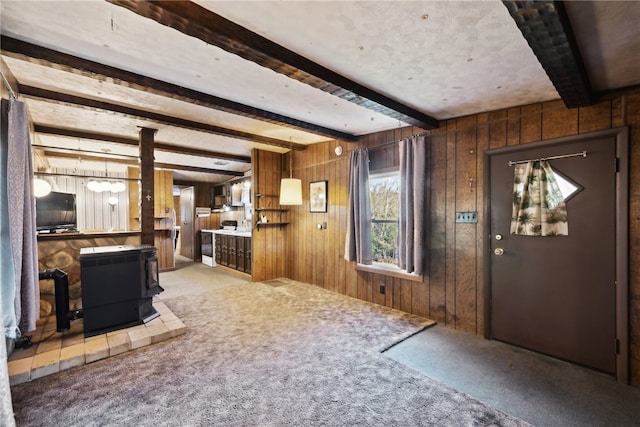 foyer entrance with beamed ceiling, wooden walls, and light colored carpet