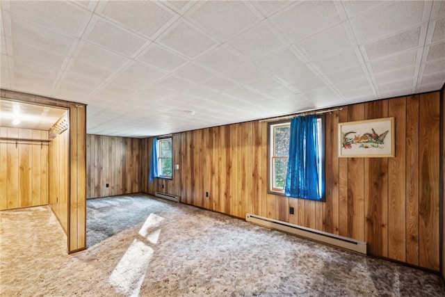 carpeted spare room featuring wooden walls and a baseboard radiator