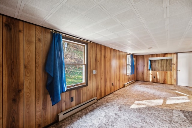 carpeted empty room with wooden walls and a baseboard heating unit