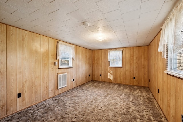 carpeted spare room featuring wooden walls