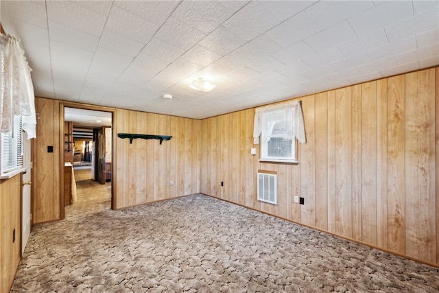 carpeted spare room with wood walls