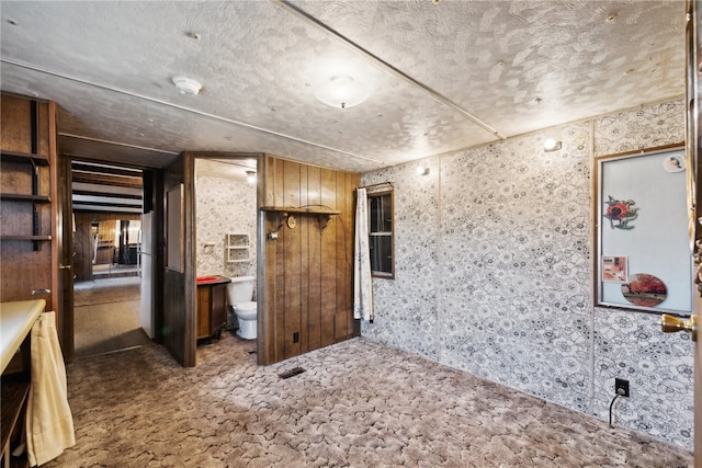 interior space with toilet, wood walls, and a textured ceiling