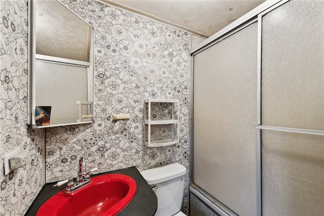 bathroom with toilet, an enclosed shower, and sink