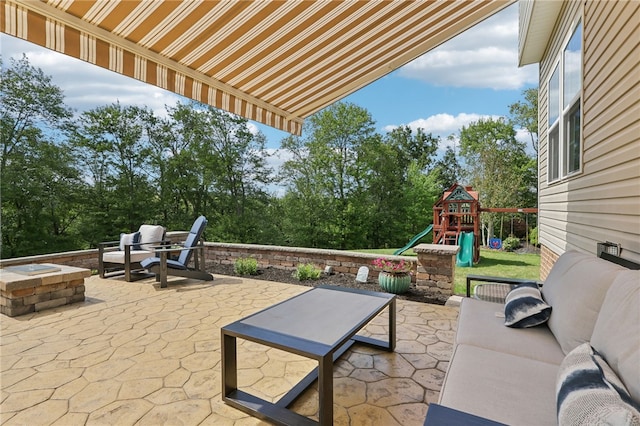 view of patio / terrace featuring a playground and an outdoor living space with a fire pit