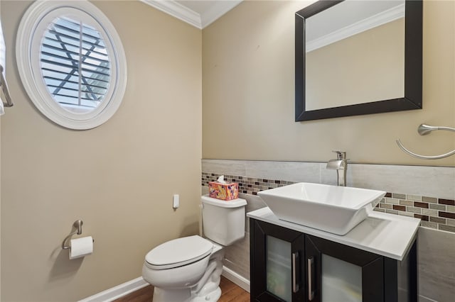 bathroom featuring toilet, wood-type flooring, vanity, ornamental molding, and tile walls