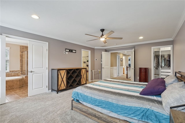 carpeted bedroom with a closet, ensuite bathroom, ornamental molding, and ceiling fan