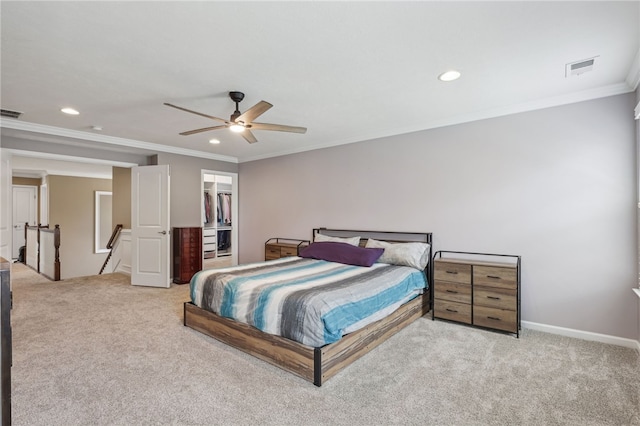 carpeted bedroom with a closet, ceiling fan, ornamental molding, and a walk in closet