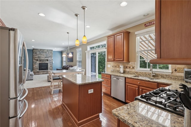 kitchen featuring sink, a stone fireplace, appliances with stainless steel finishes, and a center island