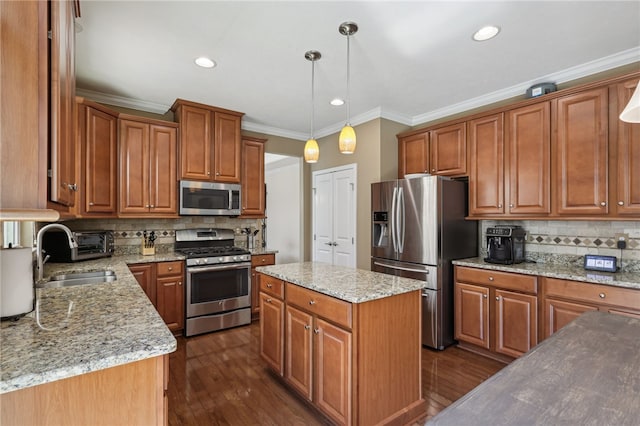 kitchen with dark hardwood / wood-style floors, hanging light fixtures, stainless steel appliances, sink, and a center island