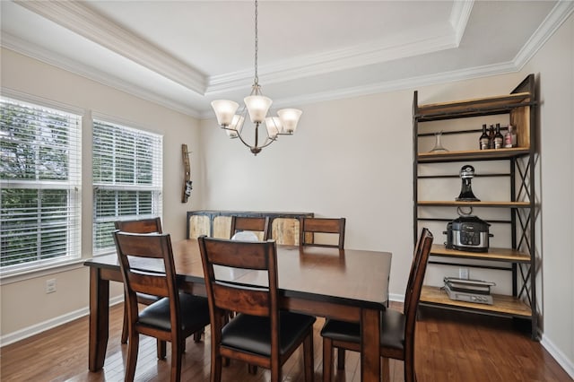 dining area featuring dark wood-type flooring, crown molding, a tray ceiling, and an inviting chandelier