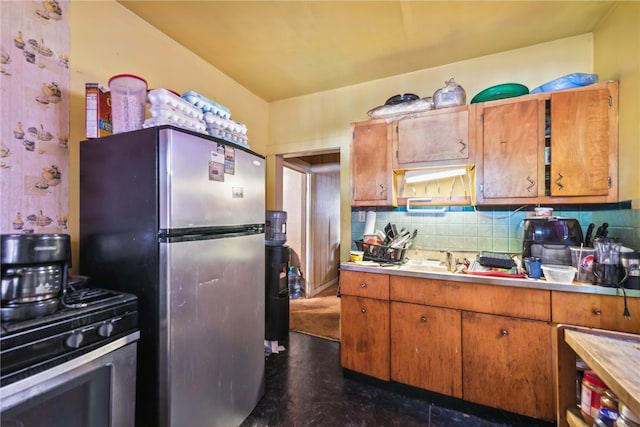 kitchen with black range with gas stovetop, tasteful backsplash, and stainless steel refrigerator