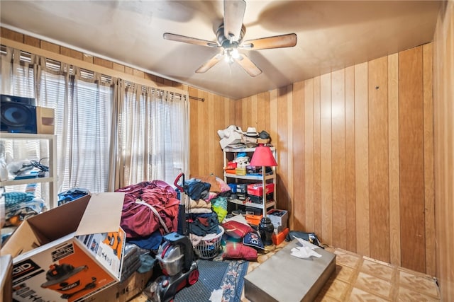 bedroom with ceiling fan and wood walls