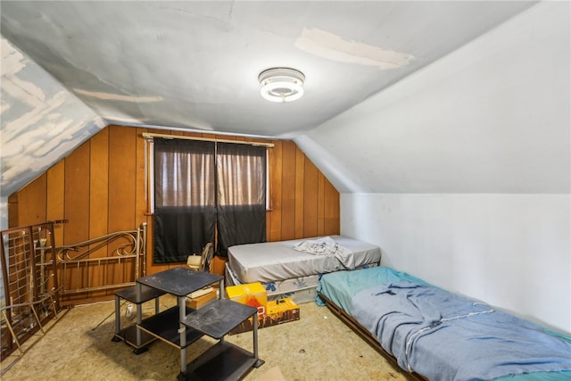 bedroom featuring lofted ceiling and wooden walls