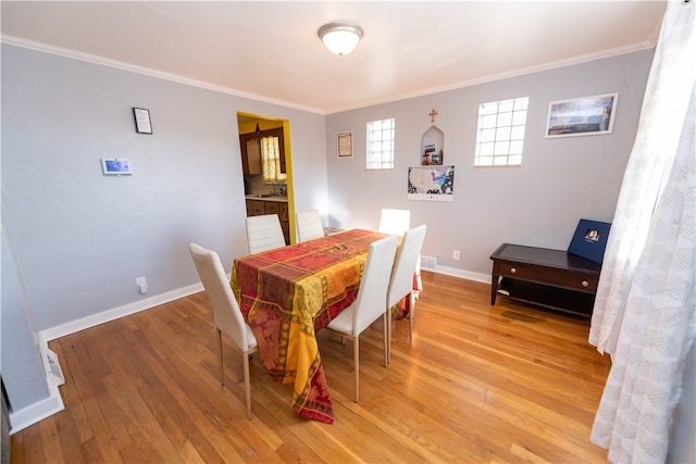 dining area with light hardwood / wood-style floors, ornamental molding, and sink